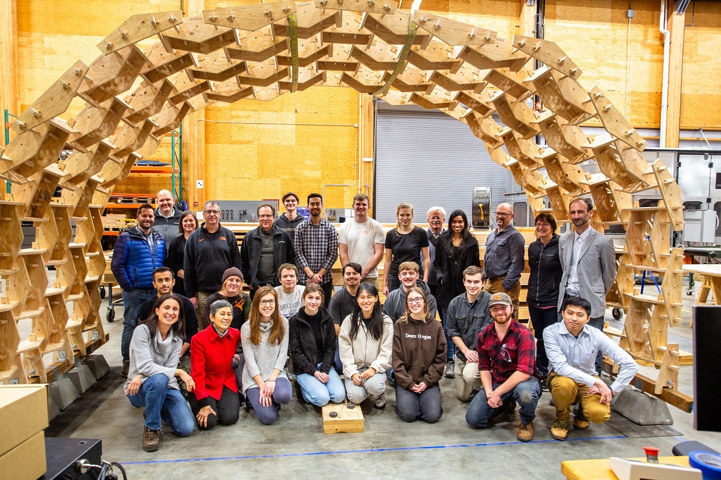 Architecture students stand under wooden creation