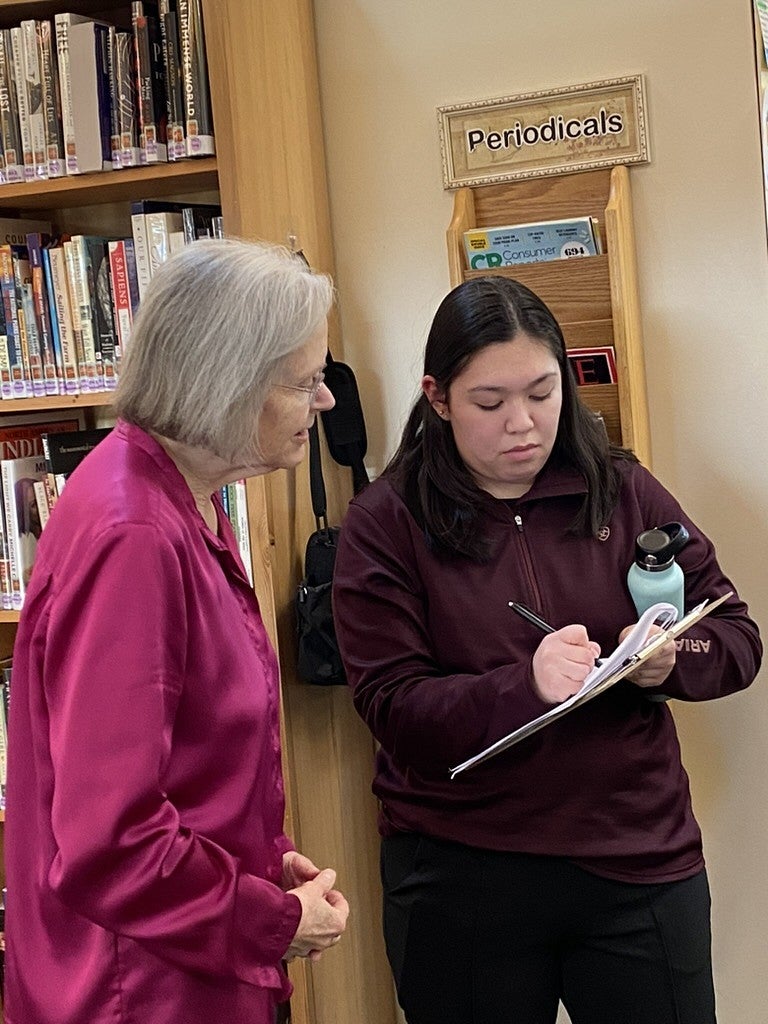 Students engages with community member and shows her information
