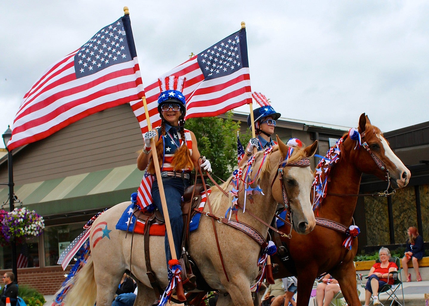 Two women dressed in American flags ride horses through a parade