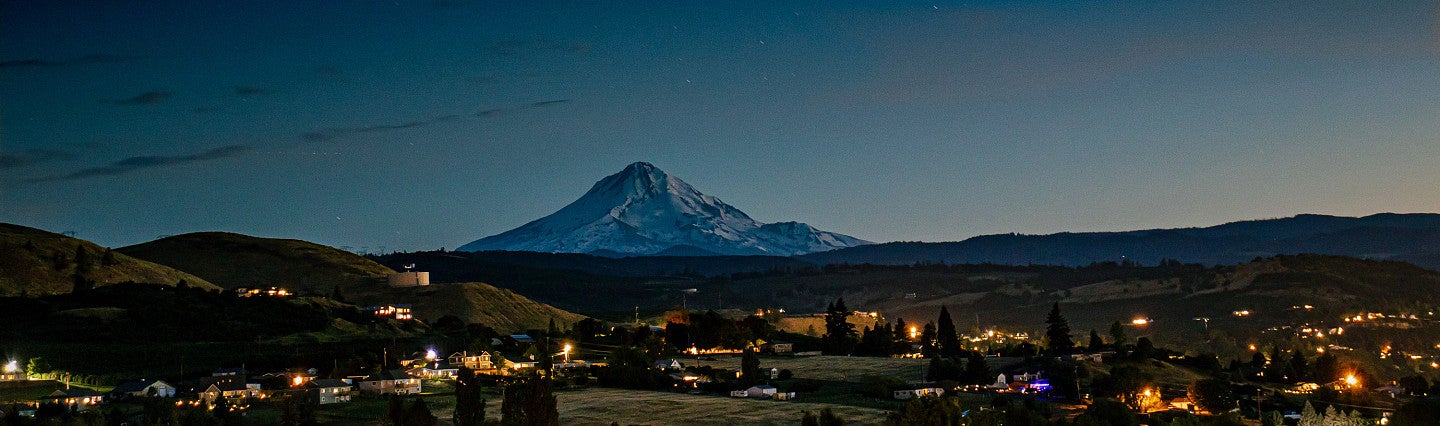 Evening view of city lights against large mountain in background