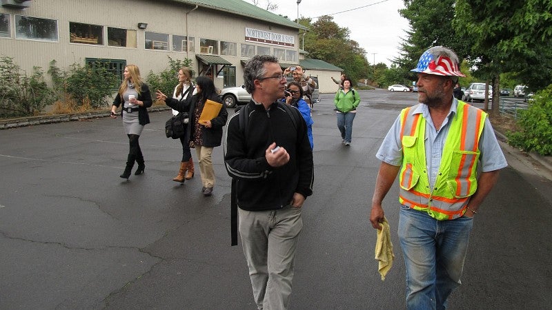 Faculty walks alongside worker with helmet on.