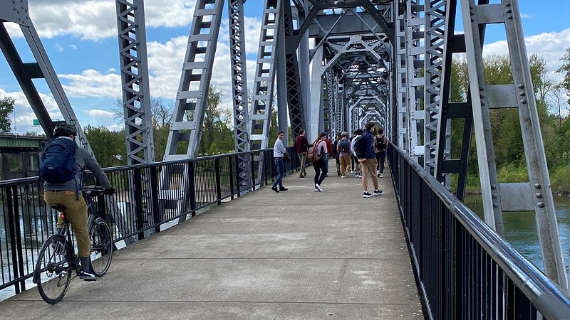 Person bikes over bridge as student group explores