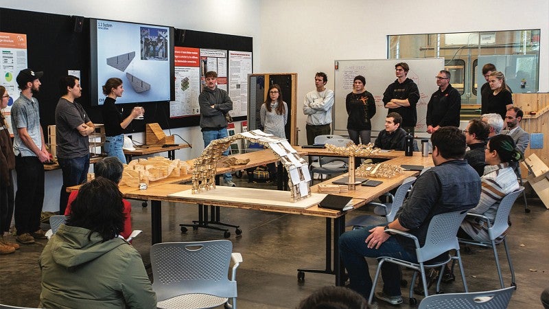 Timber tectonics students gather in classroom and discuss wooden structures