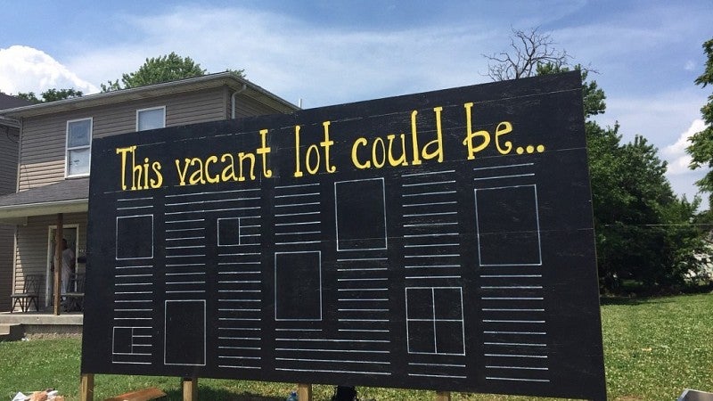 Large black sign reads "This vacant lot could be..."