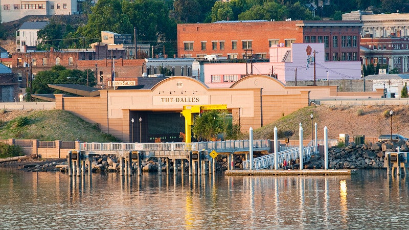 Building that reads "The Dalles" overlooking body of water