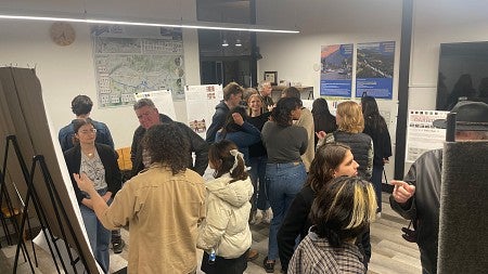 Students and community members gather in room to look at posters of student work