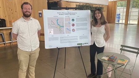 Students pose in front of presentation poster