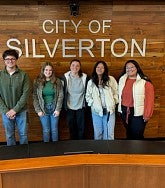 Group of students stand in front of wall that reads "City of Silverton"