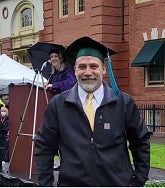 Rick Zylstra smiles while wearing cap and gown to his graduation