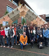 Students pose in front of wooden structure
